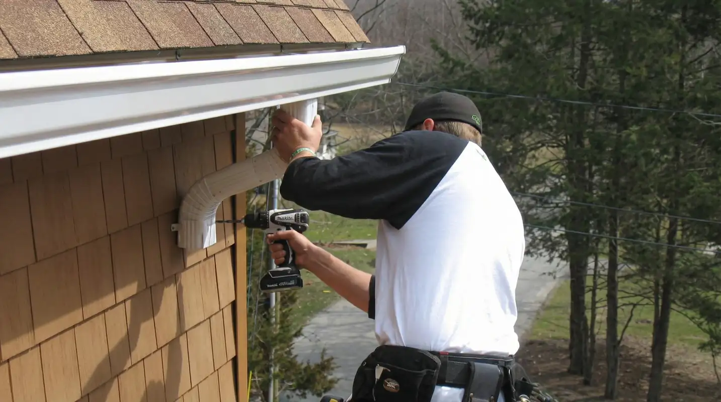 Professional contractor installing tan vinyl siding panels on a residential home exterior in Staten Island, NY